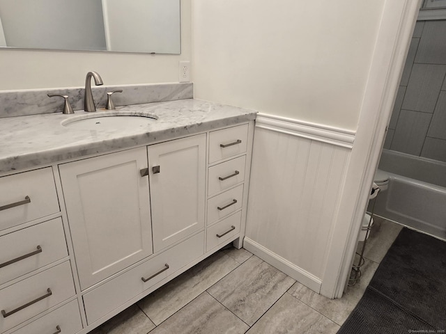 full bathroom featuring vanity, a wainscoted wall, and toilet