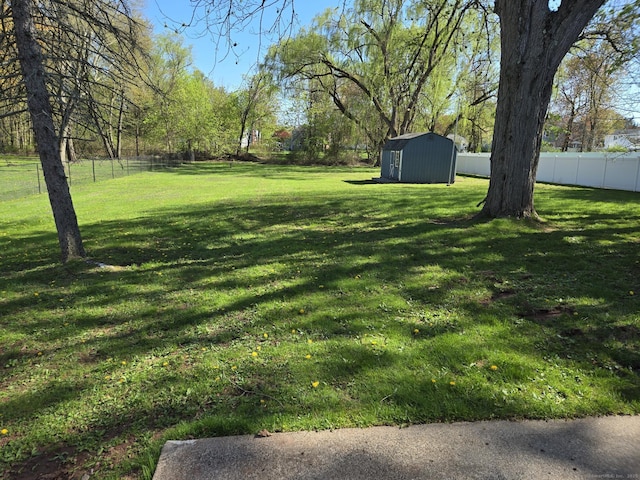 view of yard with an outdoor structure, a fenced backyard, and a storage shed
