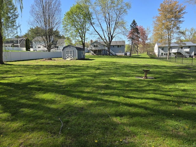 view of yard featuring a fenced backyard, a storage unit, an outbuilding, and a residential view