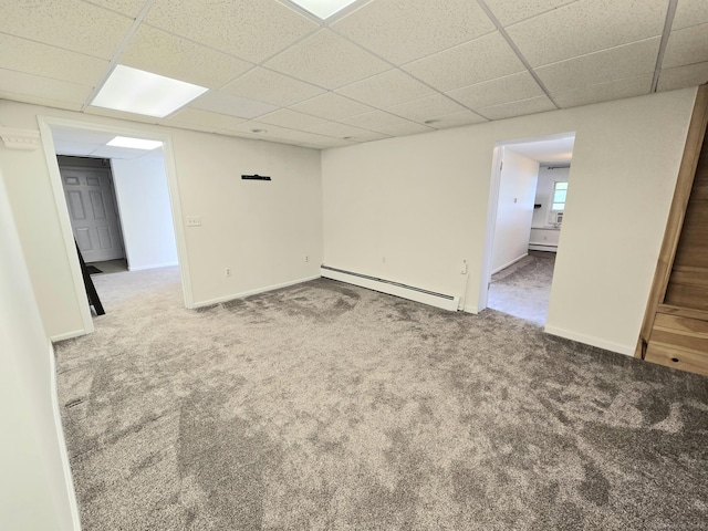 carpeted spare room featuring baseboards, a baseboard radiator, and a drop ceiling