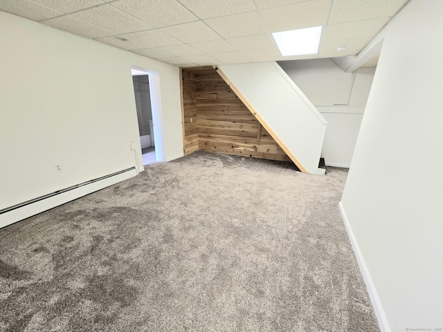 finished below grade area with wooden walls, baseboards, a paneled ceiling, and carpet