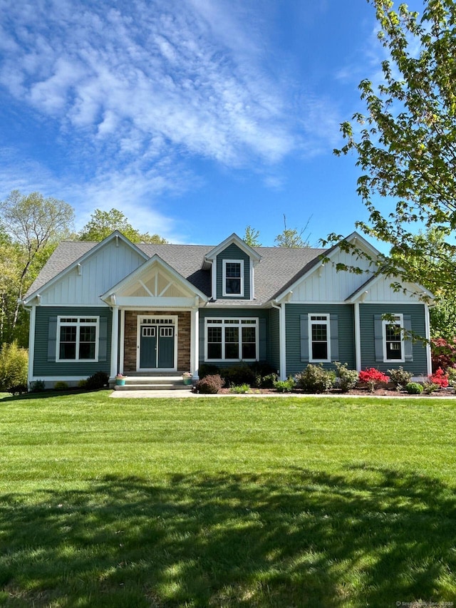 craftsman-style home featuring board and batten siding, a front lawn, and roof with shingles
