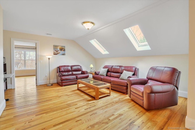living area with a skylight, vaulted ceiling, light wood-style flooring, and baseboards