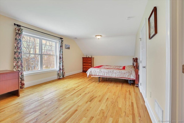 bedroom featuring wood finished floors, lofted ceiling, and baseboards