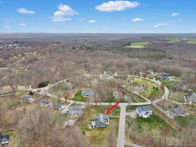 aerial view of property's location featuring a forest and nearby suburban area