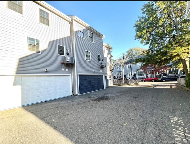 view of home's exterior featuring aphalt driveway, a residential view, and a garage