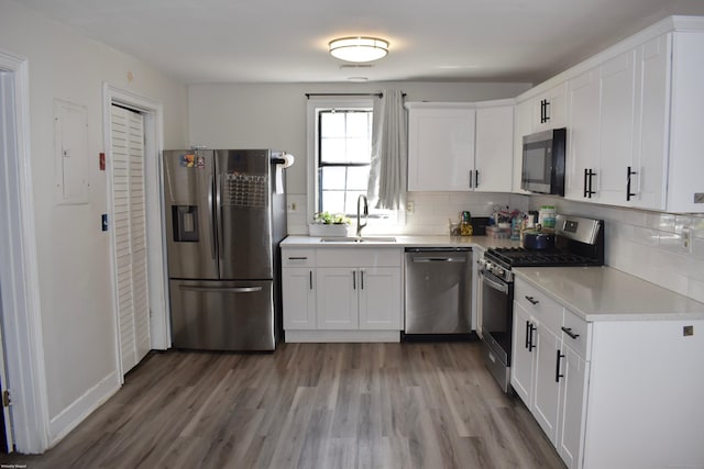 kitchen featuring appliances with stainless steel finishes, wood finished floors, a sink, and light countertops