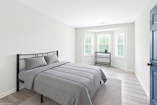 bedroom with light wood finished floors, baseboards, and visible vents