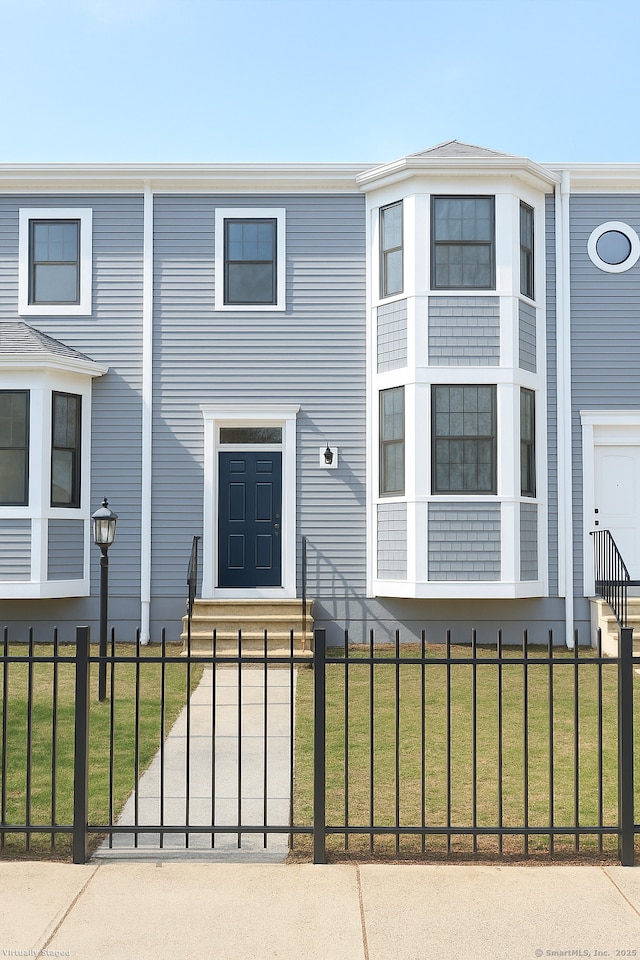 view of front of house featuring entry steps, a front lawn, and a fenced front yard