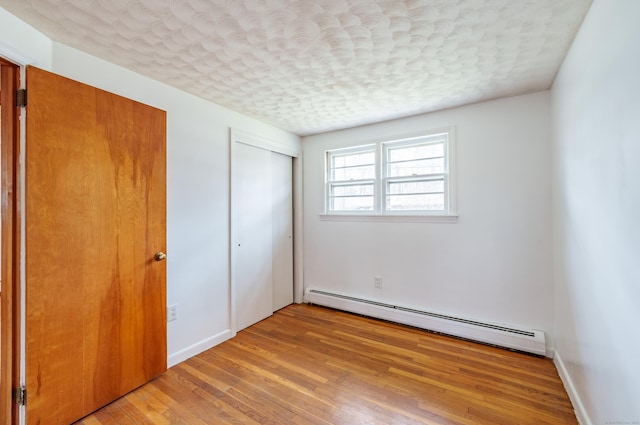 33 Wagon Rd, Enfield, CT 06082 - unfurnished bedroom featuring a baseboard heating unit, a closet, baseboards, light wood-style flooring, and a textured ceiling