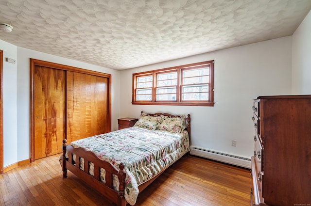 33 Wagon Rd, Enfield, CT 06082 - bedroom with a baseboard radiator, a textured ceiling, a closet, wood-type flooring, and baseboards