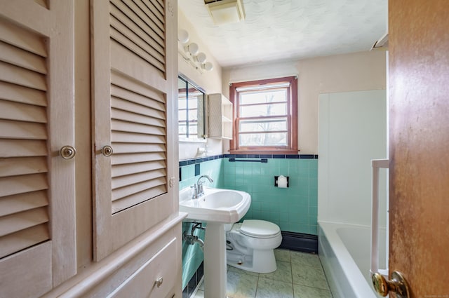 33 Wagon Rd, Enfield, CT 06082 - bathroom with tile patterned flooring, toilet, tile walls, wainscoting, and a bathtub