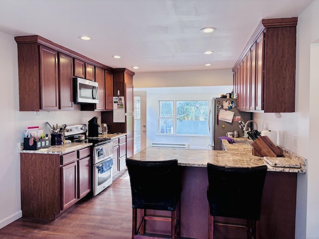 kitchen with a peninsula, stainless steel appliances, a baseboard heating unit, dark wood-style floors, and recessed lighting