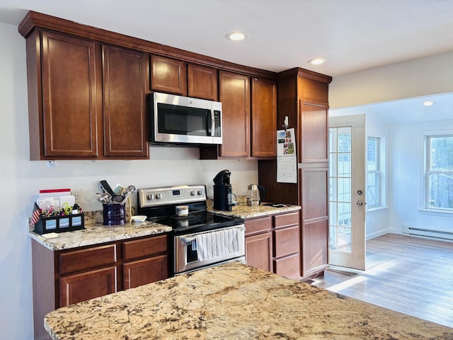 kitchen featuring recessed lighting, a baseboard radiator, light wood-style flooring, light stone countertops, and appliances with stainless steel finishes