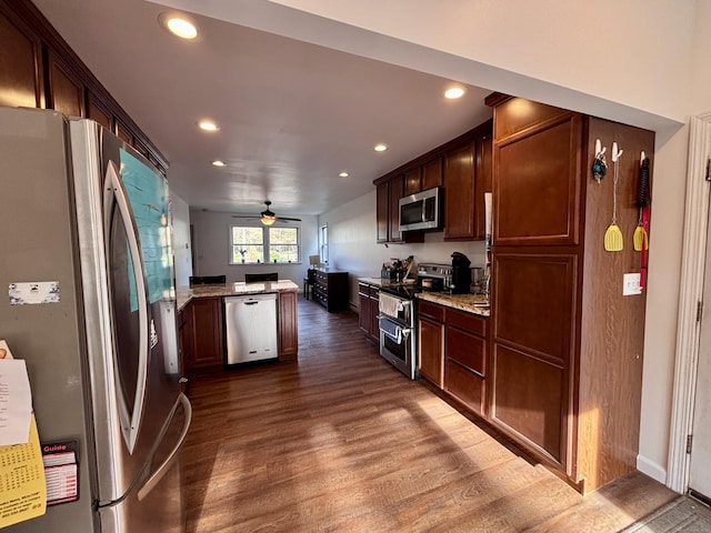 kitchen with recessed lighting, appliances with stainless steel finishes, light stone counters, and dark wood-style floors
