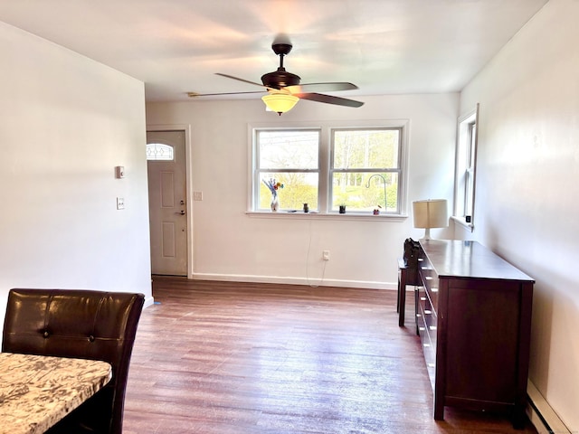 interior space with baseboards, a ceiling fan, baseboard heating, and wood finished floors