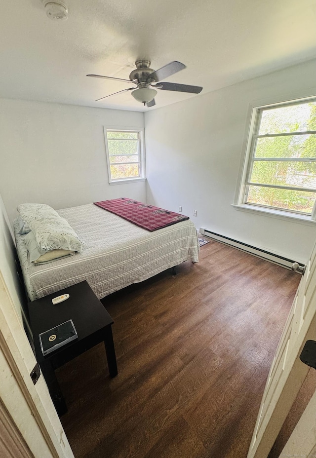 bedroom featuring ceiling fan, wood finished floors, and a baseboard heating unit