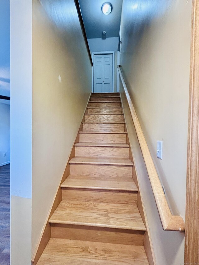 staircase featuring baseboards and wood finished floors
