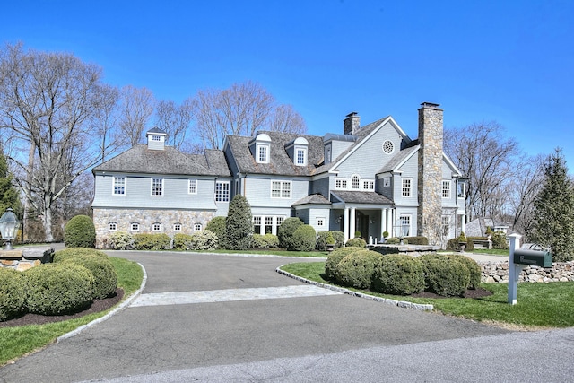17 Wardwell Dr, New Canaan, CT 06840 - view of front of house with stone siding, a chimney, and curved driveway