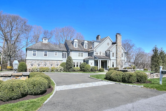 17 Wardwell Dr, New Canaan, CT 06840 - view of front facade with stone siding, a chimney, and asphalt driveway