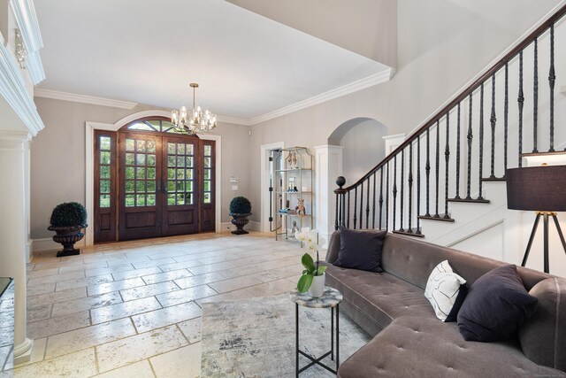 17 Wardwell Dr, New Canaan, CT 06840 - foyer entrance featuring ornamental molding, stairway, a chandelier, arched walkways, and stone tile floors