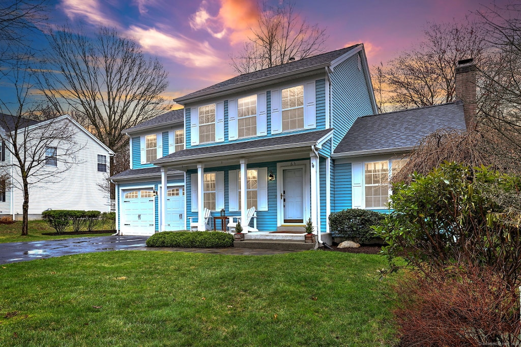 63 Chestnut Ln, Milford, CT 06461 - traditional-style home with a porch, a garage, a shingled roof, a front yard, and aphalt driveway