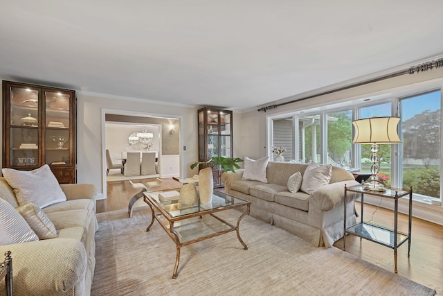 living area with light wood-style flooring, a chandelier, and ornamental molding