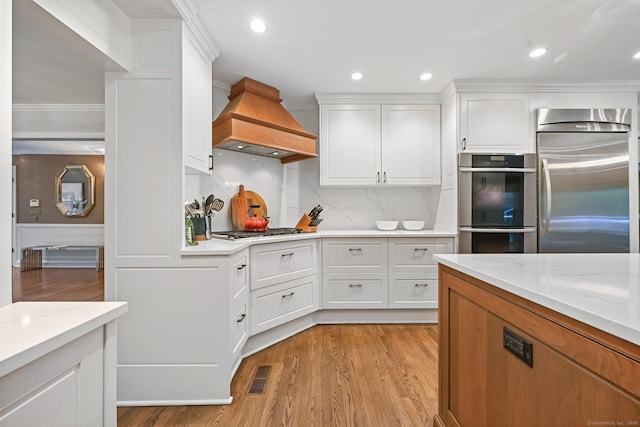 kitchen featuring premium range hood, appliances with stainless steel finishes, light wood-type flooring, white cabinets, and recessed lighting