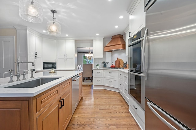 kitchen featuring stainless steel appliances, a sink, premium range hood, recessed lighting, and light wood finished floors