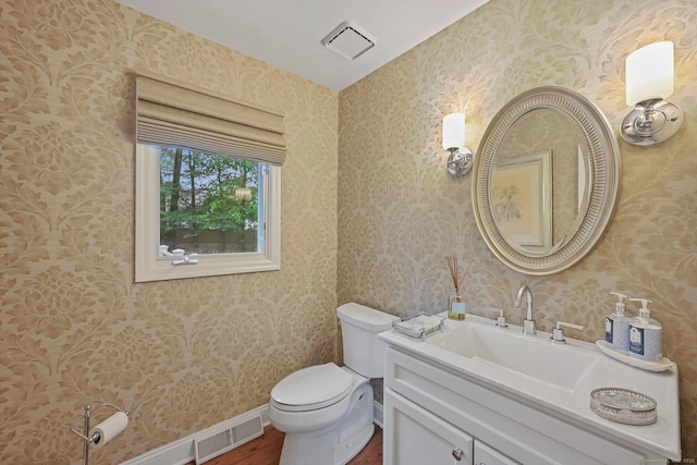 half bath featuring wallpapered walls, wood finished floors, toilet, vanity, and baseboards