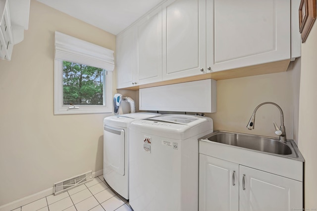 washroom with cabinet space, independent washer and dryer, baseboards, and light tile patterned floors