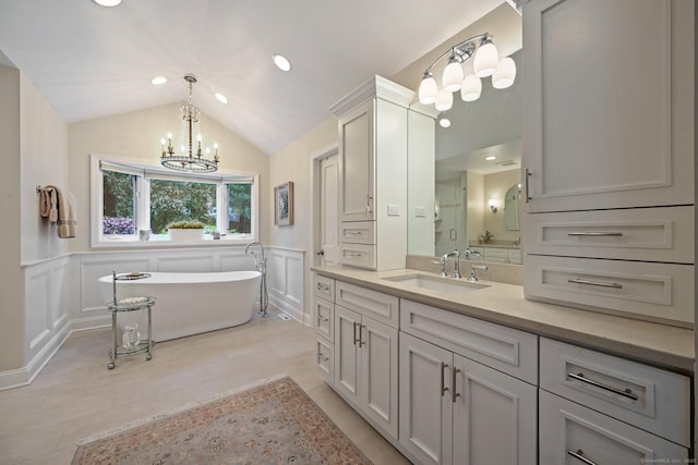 bathroom featuring a chandelier, a decorative wall, wainscoting, a freestanding tub, and lofted ceiling