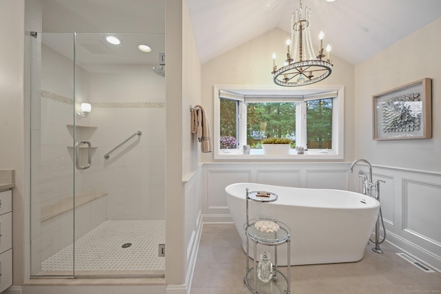 full bathroom featuring a decorative wall, a stall shower, a freestanding bath, vaulted ceiling, and a chandelier