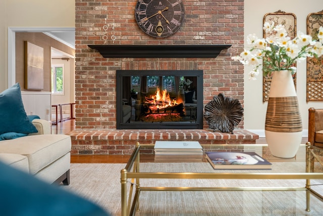living area with a fireplace, wood finished floors, and ornamental molding