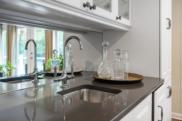 kitchen view of white cabinetry, a sink, glass insert cabinets, and beverage cooler