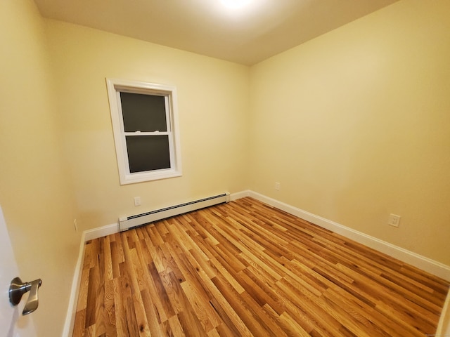 spare room with baseboards, light wood-style floors, and a baseboard radiator