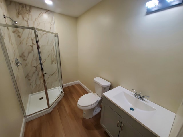 bathroom with baseboards, a marble finish shower, toilet, wood finished floors, and vanity