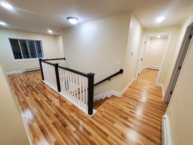 hallway featuring an upstairs landing, light wood-style floors, recessed lighting, and a baseboard heating unit