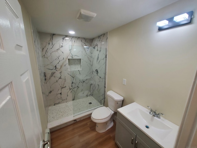full bathroom featuring wood finished floors, toilet, vanity, and a marble finish shower