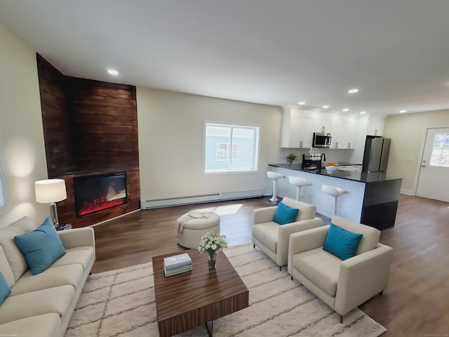 living room with a baseboard heating unit, recessed lighting, wood finished floors, and a fireplace