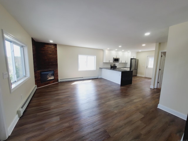 unfurnished living room featuring a baseboard radiator, a baseboard heating unit, recessed lighting, dark wood finished floors, and a fireplace