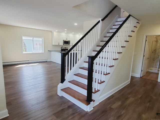 stairs with recessed lighting, baseboard heating, wood finished floors, and baseboards