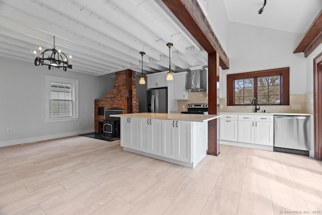 280 Mill Rd, North Haven, CT 06473 - kitchen featuring appliances with stainless steel finishes, a wood stove, wall chimney exhaust hood, light countertops, and tasteful backsplash