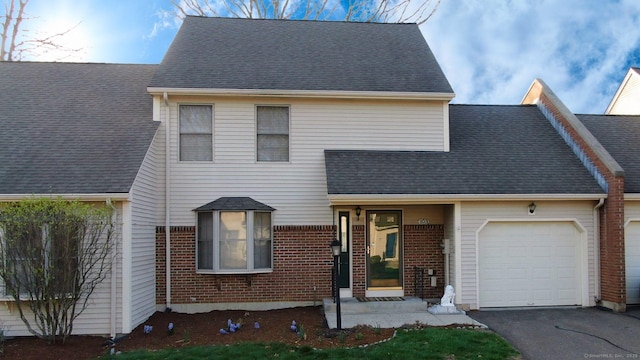 view of front of property featuring brick siding, a shingled roof, a garage, and aphalt driveway