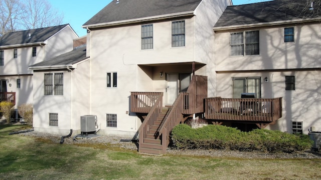 rear view of property with roof with shingles, central air condition unit, stairs, a deck, and a lawn