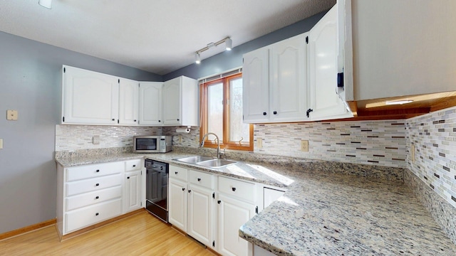 kitchen featuring stainless steel microwave, tasteful backsplash, white cabinetry, dishwasher, and a sink