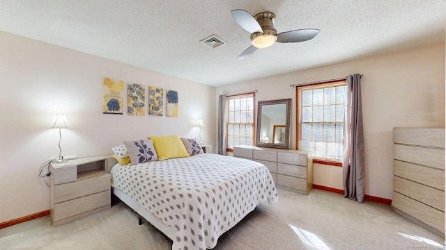 bedroom with light carpet, visible vents, baseboards, and ceiling fan