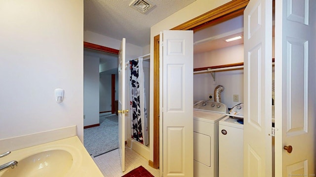 laundry room featuring a textured ceiling, visible vents, laundry area, washer and dryer, and a sink