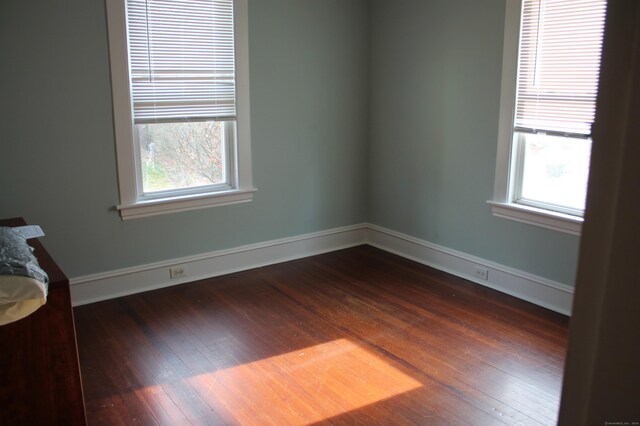spare room featuring dark wood-style flooring and baseboards