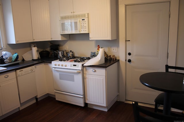 kitchen featuring dark wood finished floors, dark countertops, white appliances, and white cabinets